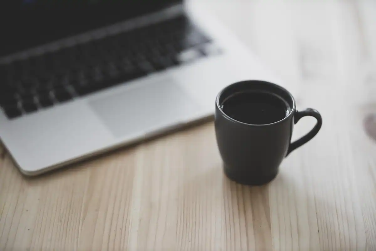 Două cești de cafea și un caiet pe masă, pentru discuția despre bugetul în cuplu