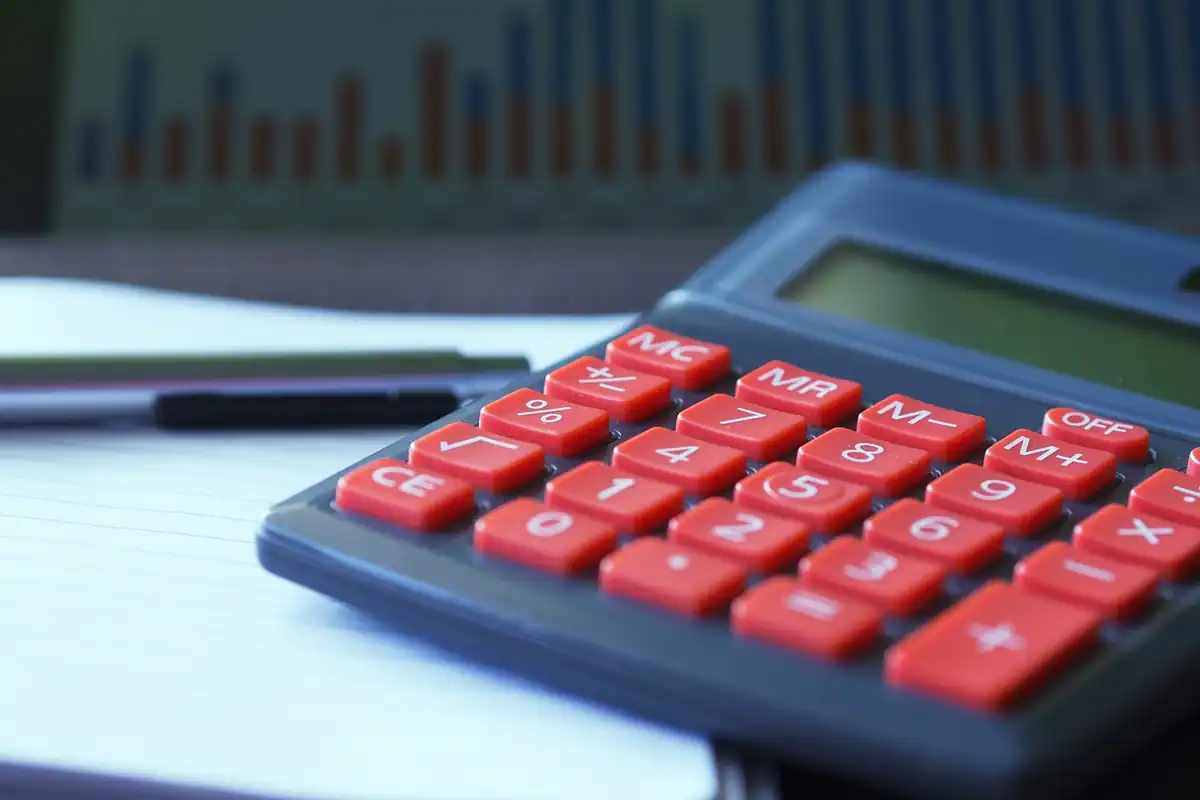 Calculator cu taste roșii pe un blat, cu un grafic estompat în fundal