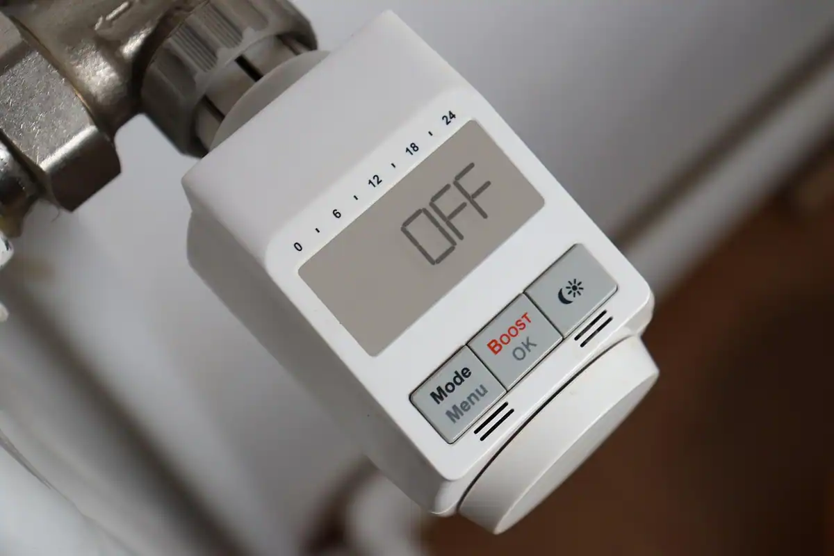 Termostat digital alb montat pe un calorifer, afișând temperatura reglată