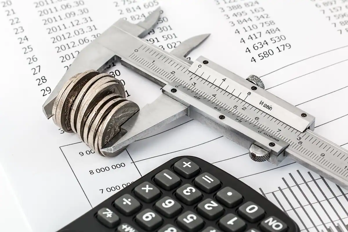 Teanc de monede și un calculator pe un birou, pentru calculul consolidării datoriilor