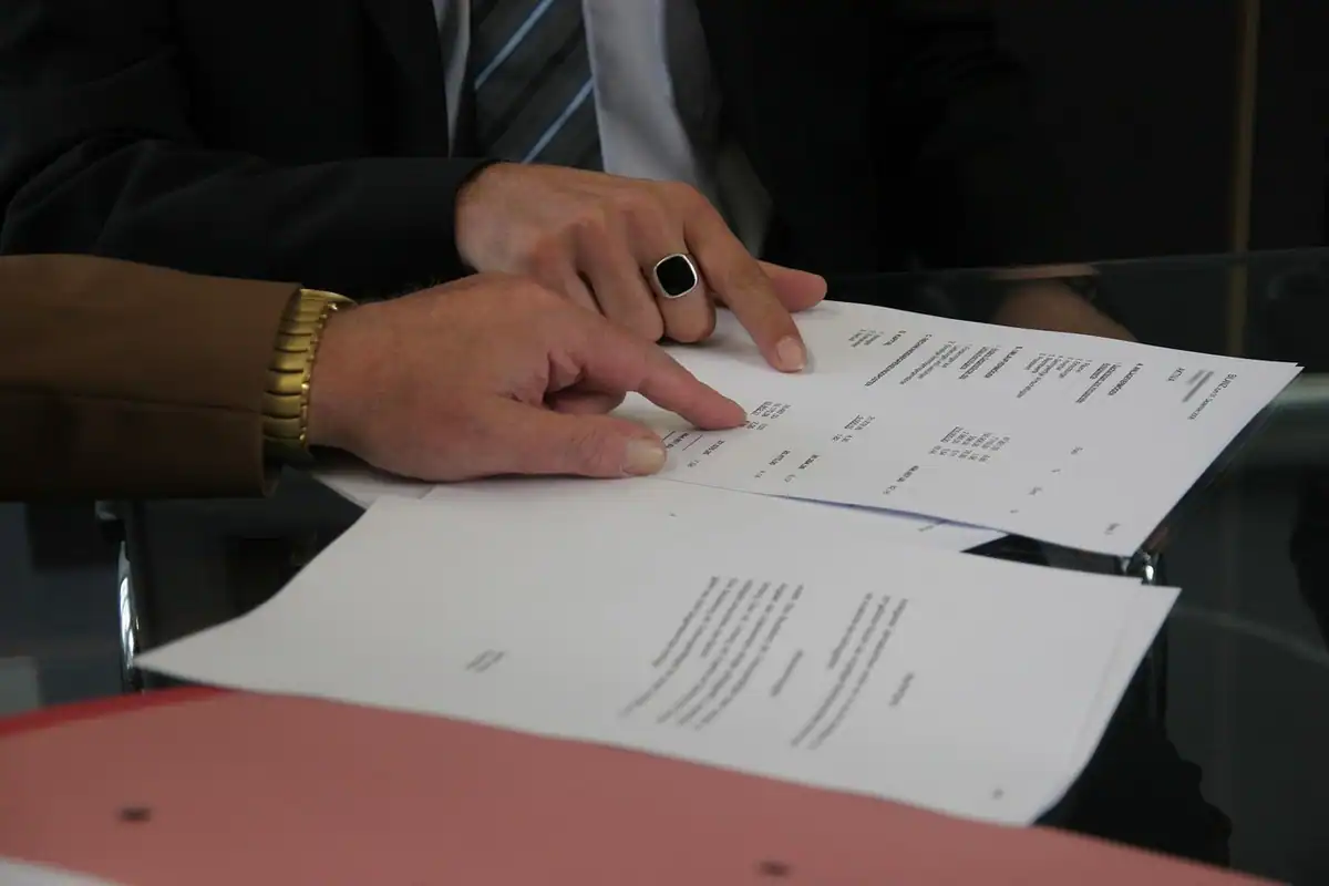 Mâini care analizează împreună documente pe o masă, la o discuție despre un plan de plată