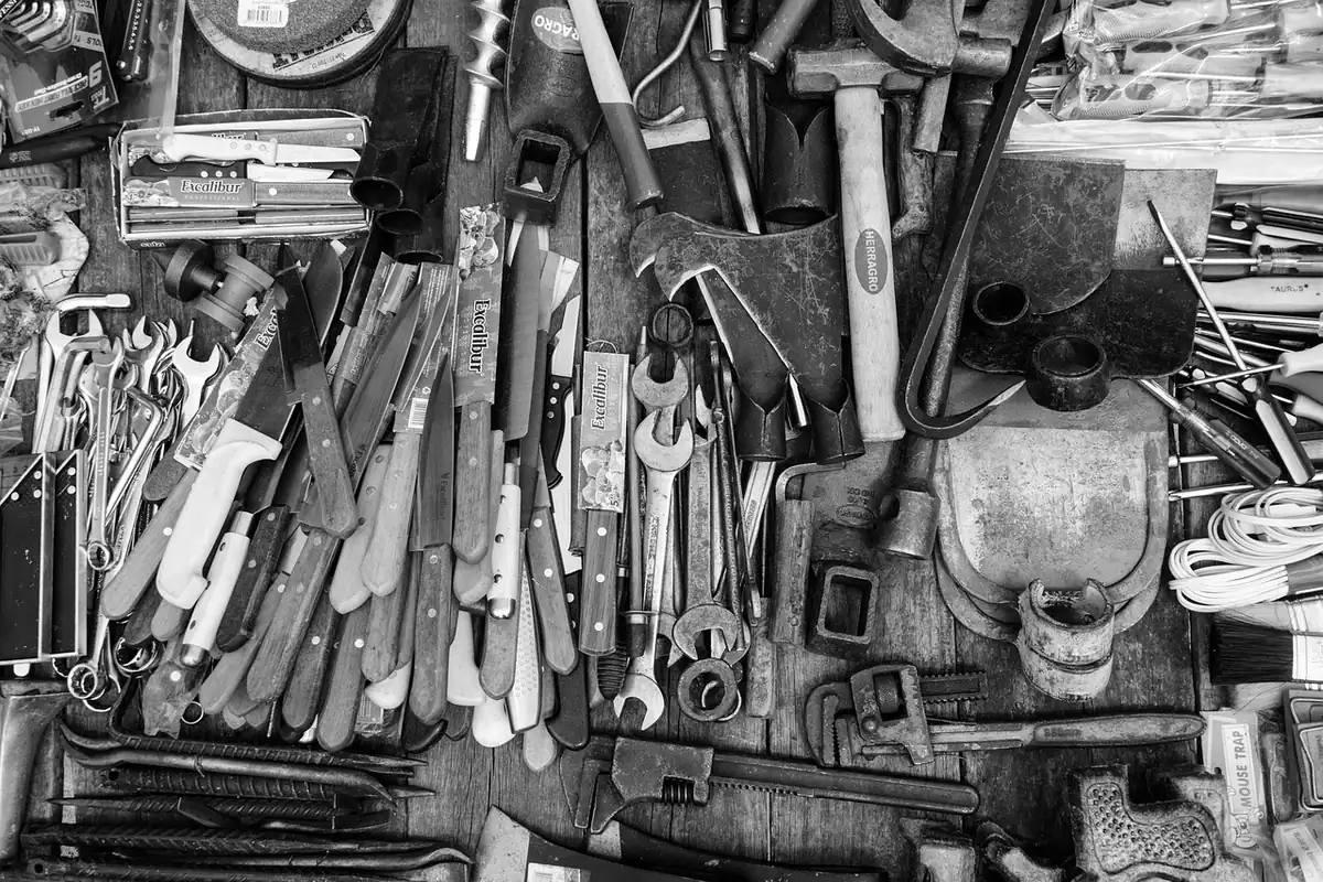 Unelte de reparat, chei fixe și clești, împrăștiate într-un atelier, în alb-negru