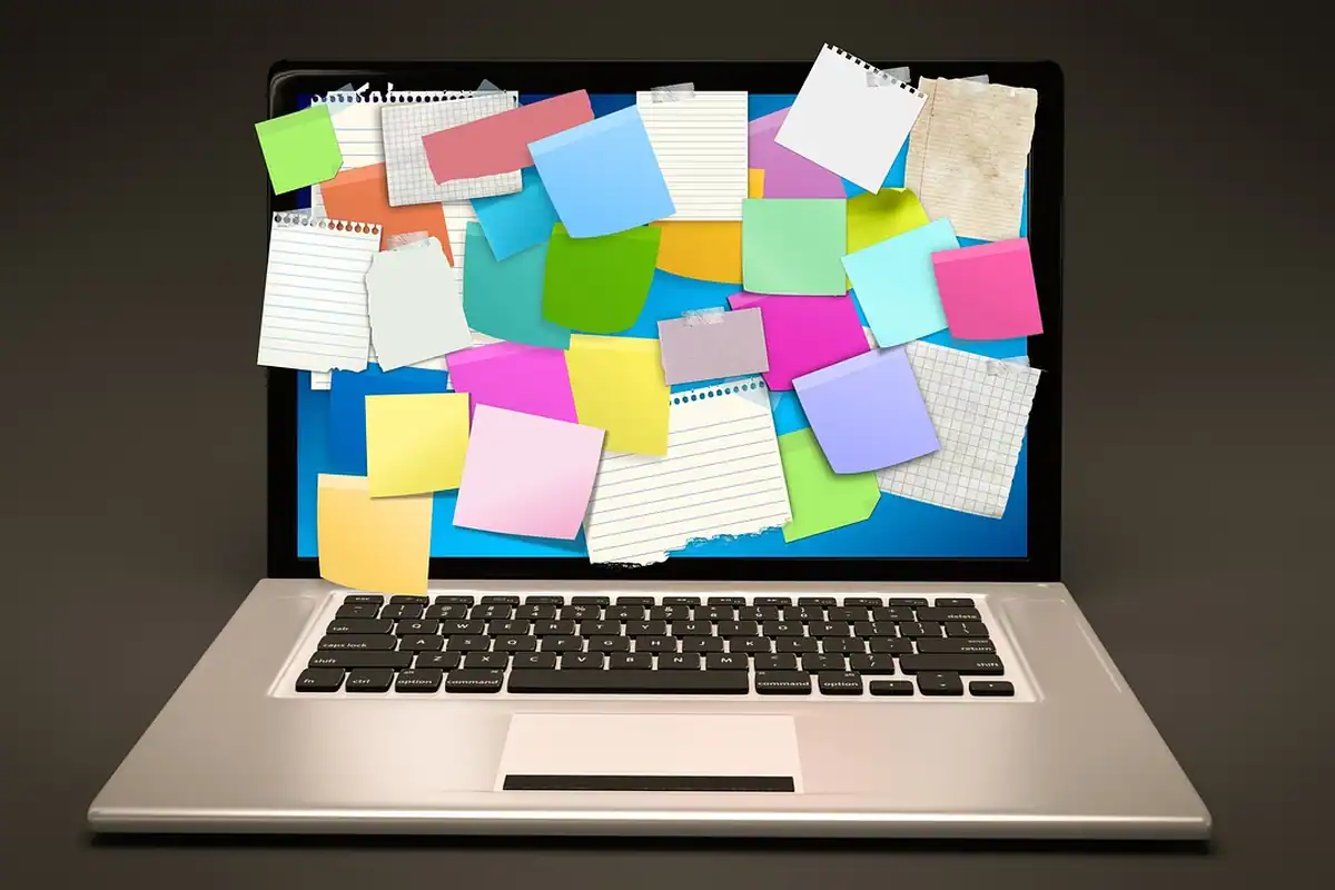 Notițe adezive lipite pe un laptop, pentru planificarea primelor obiective financiare